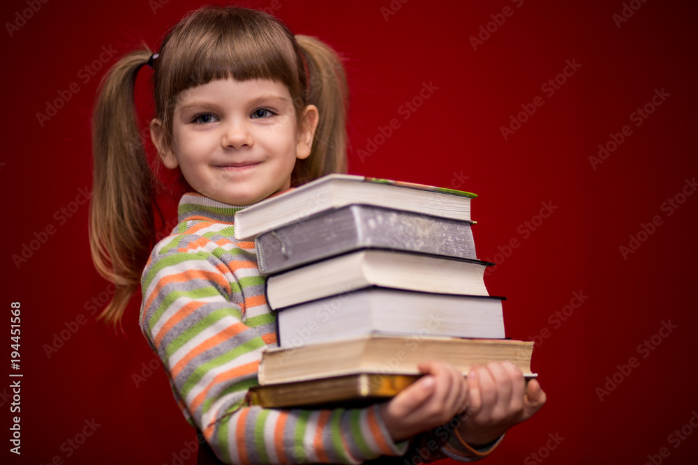 Portrait of cheerful little girl isolated on red hold many books. Concept of knowledge or school. Book lover. Portrait of cheerful little girl isolated on red hold many books. Concept of knowledge or school. Book lover.