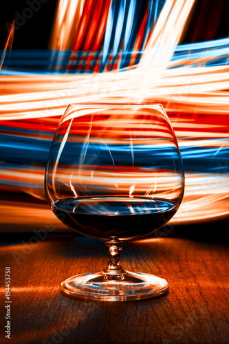 A glass of cognac on bright background with bokeh effect.