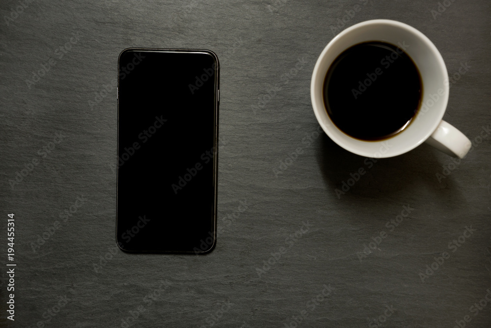 Mobile phone and cup of coffee - on dark slate, view from above - with copy space Mobile phone and cup of coffee - on dark slate, view from above - with copy space
