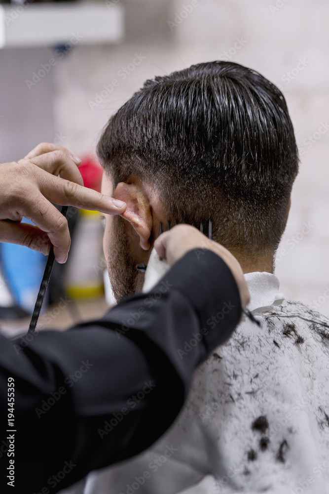 Hairdresser cutting hair to a client with an electric machine Hairdresser cutting hair to a client with an electric machine