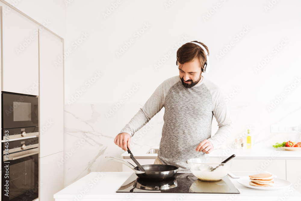 Portrait of a smiling young man cooking pancakes Portrait of a smiling young man cooking pancakes