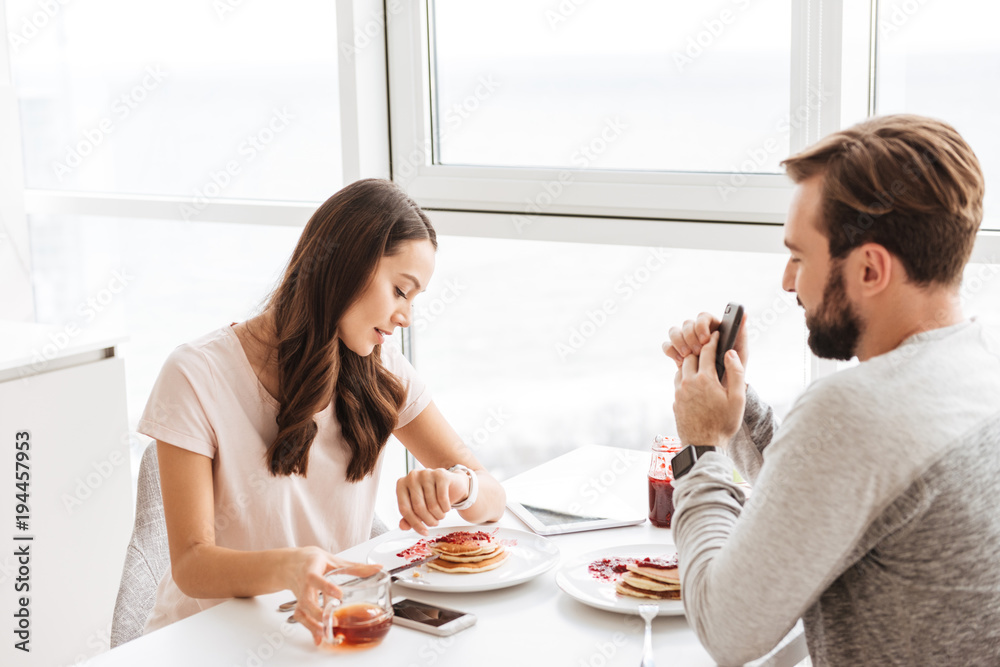 Pretty young couple having breakfast while sitting together