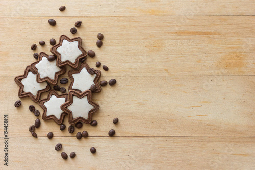 Chocolate cookies in the form of stars with a white filling on a light wooden background and decorated with coffee beans. Copy text menu food background.Top View, Flat.