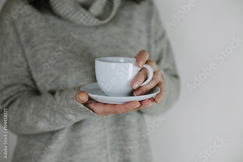 Breakfast and coffee theme: woman's hand holding white empty coffee or tea cup, advertising coffee or tea.