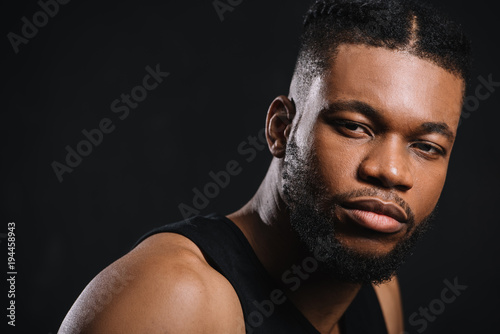 close-up portrait of handsome young athletic african american man looking at camera isolated on black