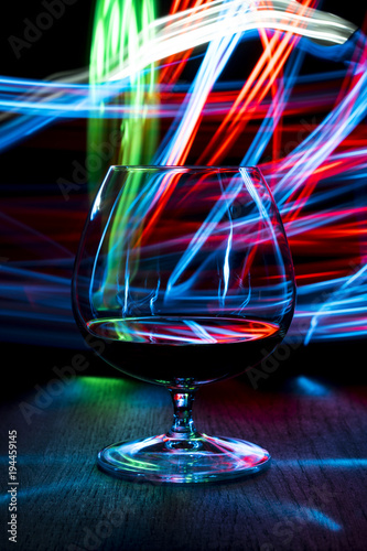 A glass of cognac on bright background with bokeh effect.