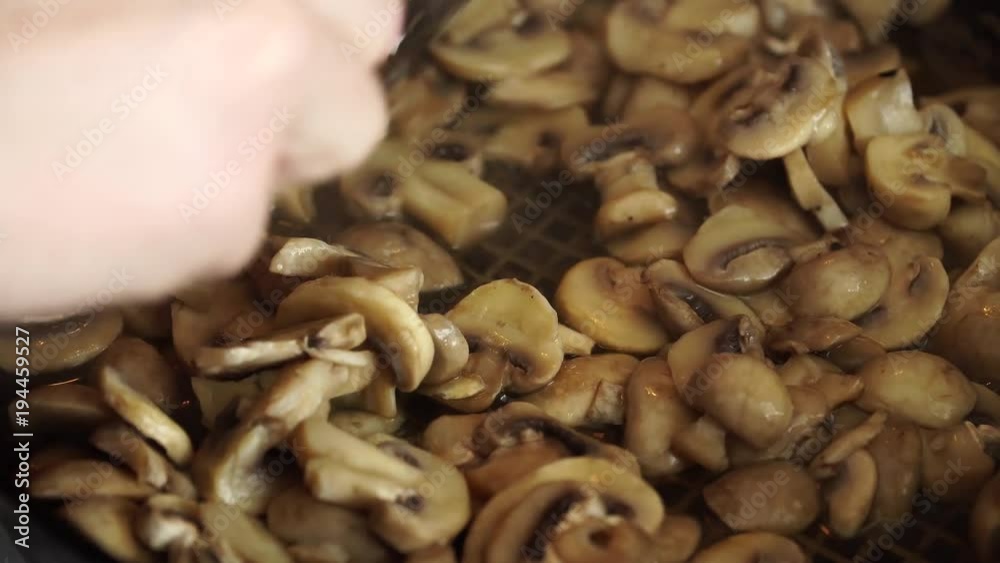 Woman with spoon shuffles carefully mushrooms on pan Woman with spoon shuffles carefully mushrooms on pan