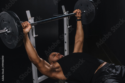 muscular young african american sportsman lifting barbell