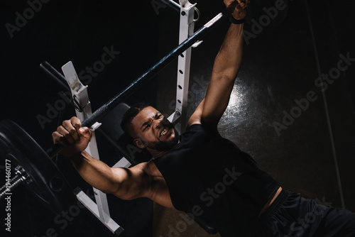 high angle view of young african american sportsman lifting barbell