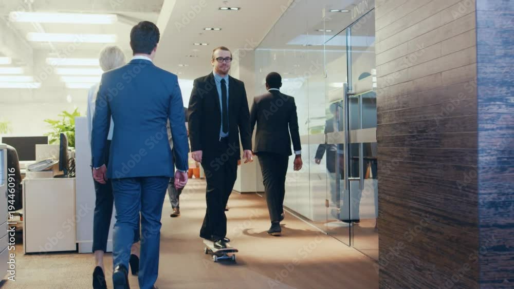 Stylish Suited Businessman Rides Skateboard Through the Corporate Building Hallway. Stylish Glass and Concrete Building with Multicultural Crowd of Business People. Shot on RED EPIC-W 8K. Stylish Suited Businessman Rides Skateboard Through the Corporate Building Hallway. Stylish Glass and Concrete Building with Multicultural Crowd of Business People. Shot on RED EPIC-W 8K.