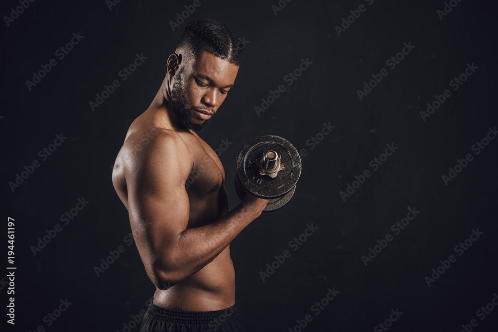 side view of muscular shirtless african american man exercising with dumbbell isolated on black