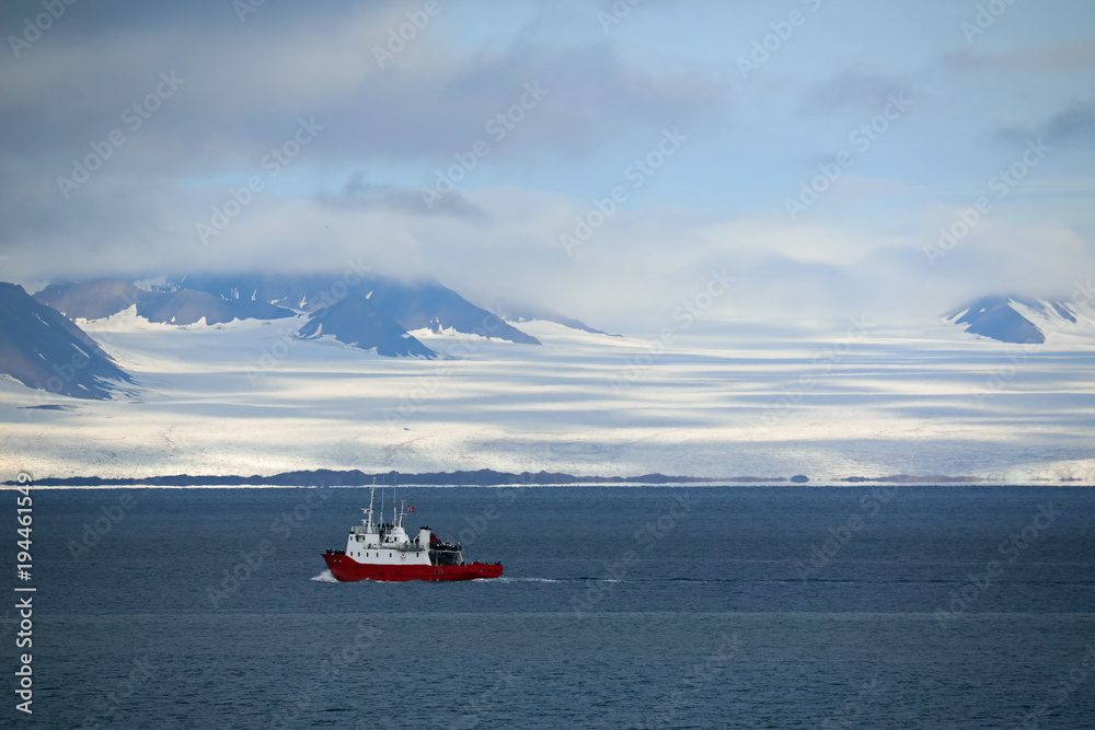 Red boat passing around glacier at Svalbard, Spitsbergen
