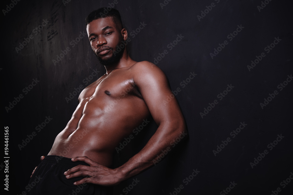 handsome shirtless muscular african american man looking at camera on black