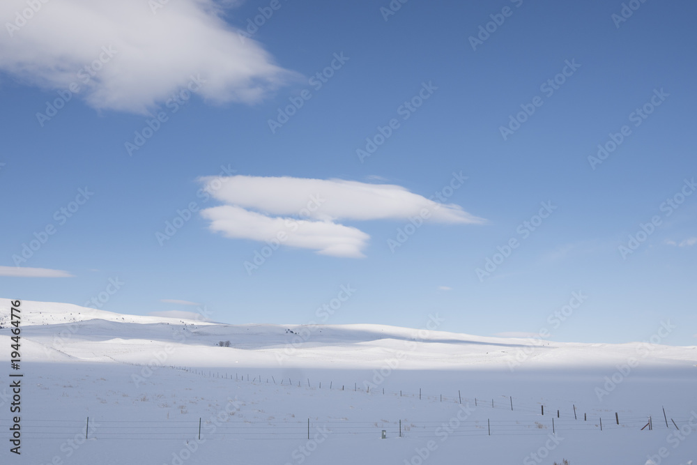 Clouds and fence line in winter landscape