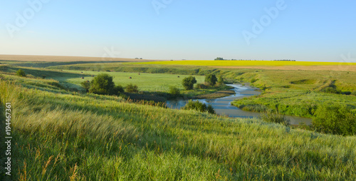 Sunny summer landscape.Green hills,fields and meadows.River Upa in Tula region,Russia.Sunrise.Quiet morning.Calm.Warm sunlight.Cloudless clear blue sky. 