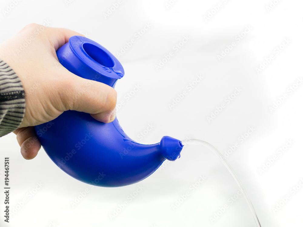 Use of a device for washing the nose. The hand holds the device with a pouring solution for