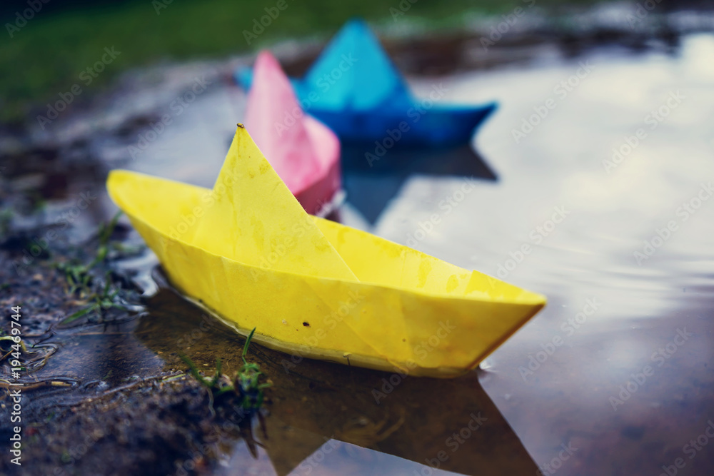 Barco de papel de colores sobre un charco de lluvia 