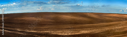 Panorama of arable land over amazing clouds sky