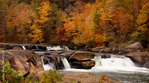 Fototapeta Naklejka Na Ścianę i Meble -  River waterfall over large rocks with Autumn scenery.