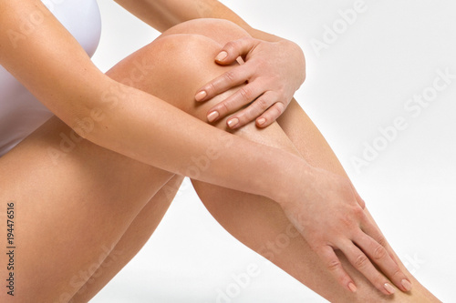 Beautiful female legs. A woman is hugging her knees. Photos in the studio close up
