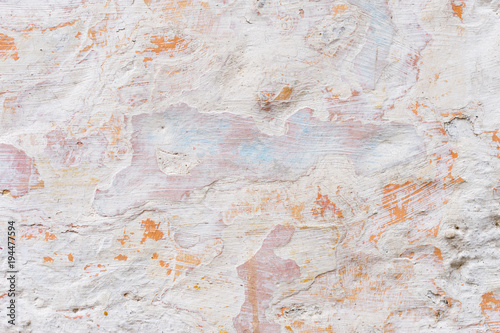 Textured grunge background. Volumetric plastered wall with a multilayer cracked coating. Orange chips on the whitewashed wall. Grunge texture with a deep pattern