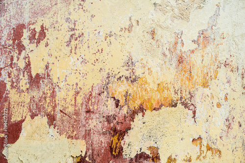 Textured background of multi-layer flaking paint on the wall. Mixing different colors of paints in the cleaved layers on the surface. Grunge texture with a deep pattern