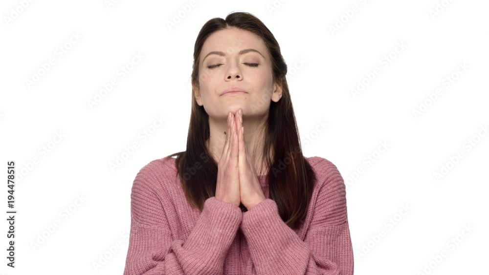 Portrait of praying mature woman in pink sweater putting hands together, and begging god for luck, over white background. Concept of emotions Portrait of praying mature woman in pink sweater putting hands together, and begging god for luck, over white background. Concept of emotions
