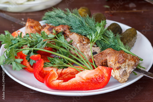 In a white plate are fresh vegetables with meat cooked on the grill.