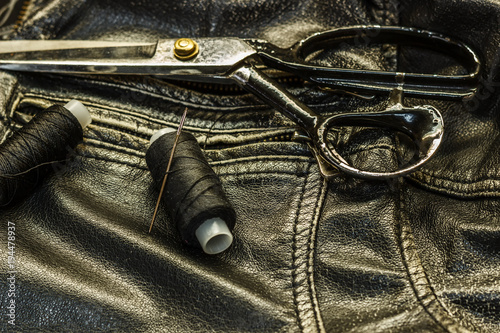 Sewing leather jacket, repair of leather jacket scissors, thread, close-up. Products of leather.