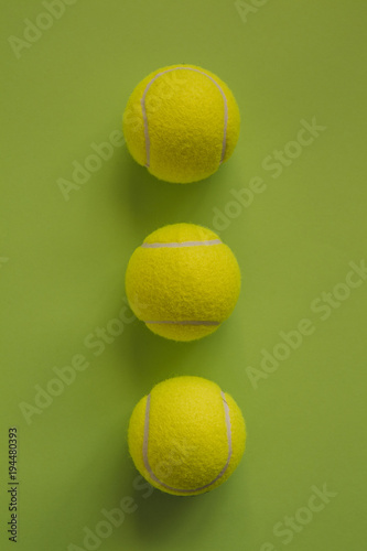 Three tennis balls on a green background.