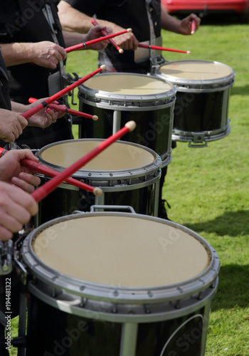 Close up of drummers playing in a traditional Scottish pipe band. Outdoor highland music festival with marching drummers holding red drum sticks. Hands holding drum sticks.