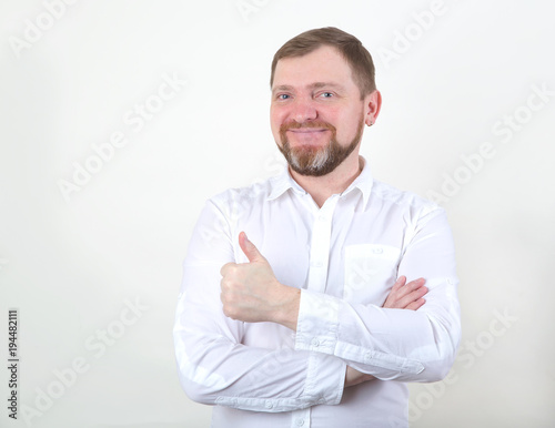 Bearded man in a white shirt shows a gesture with his thumb up: Excellent, everything is very good! © A Stock Studio