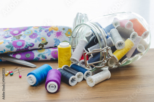 Rolls of colored yarn coming out of glass jar.