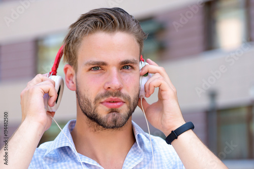 Young man listening music with headphones on urban background