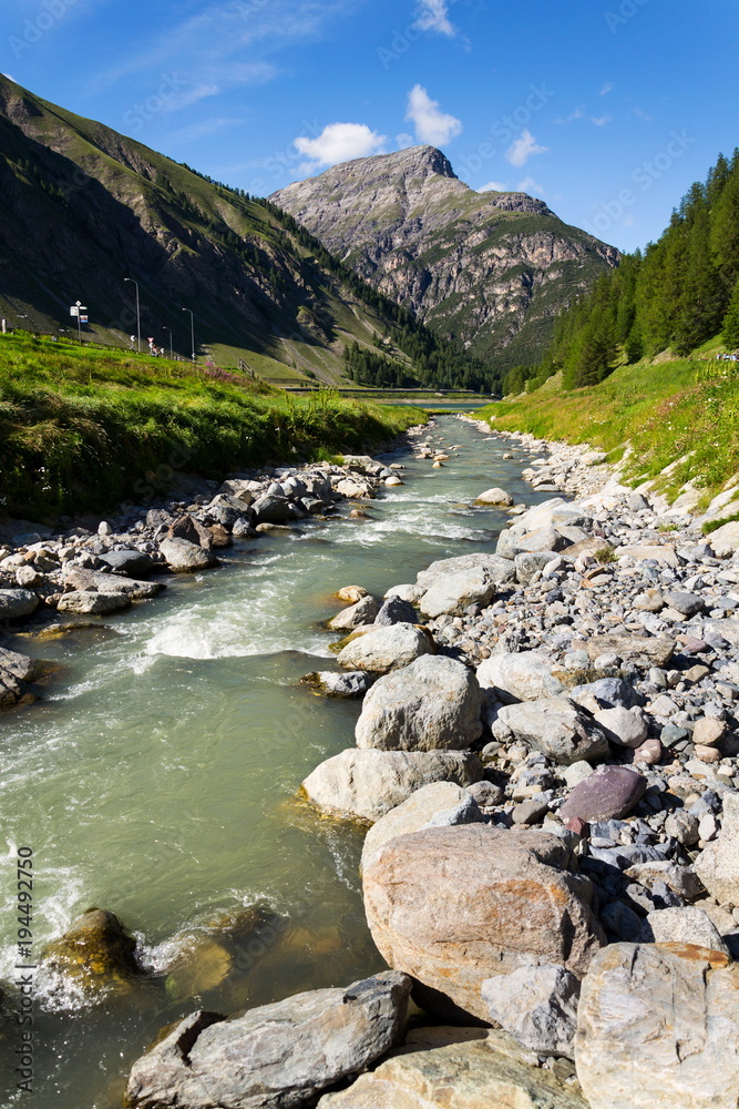Spol River flowing in Lake Livigno with Corno Brusadella Mountain in