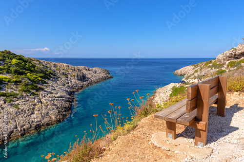 Bench on cliff with view of bay with crystal sea water. Korakonisi Island on western side of Zakynthos. Zante, Greece