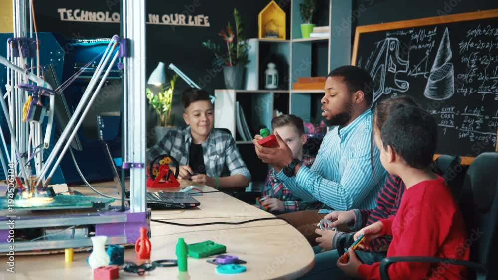 African-american man conducting class with group of kids having club and discussing robotics and technologies. Static 4K shot on Red cinema camera.