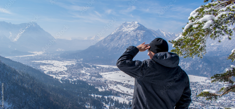 Mann genießt die Aussicht und schaut herab auf Garmisch-Partenkirchen und Farchant