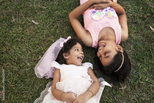 Teenage girl and kid lying down on glass field and sharing happy moments photo