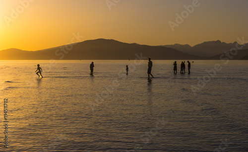 People walking in low tide during sunset