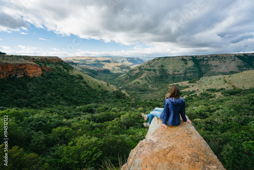 Hiker sitting on a rock outcrop overlooking a scenic mountain valley