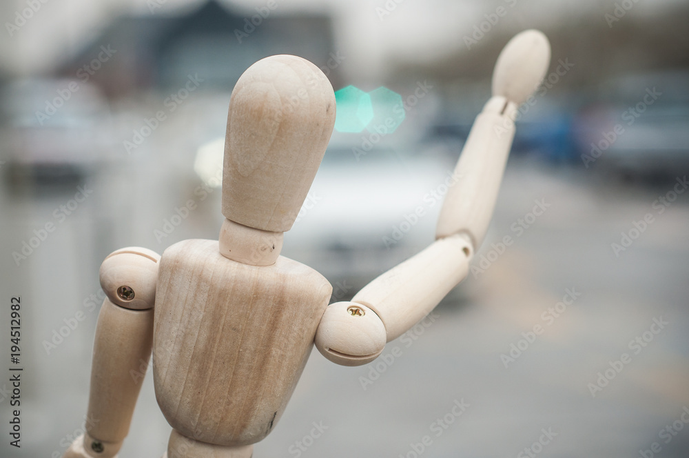 closeup of wooden puppet calling a taxi - concept tourism closeup of wooden puppet calling a taxi - concept tourism