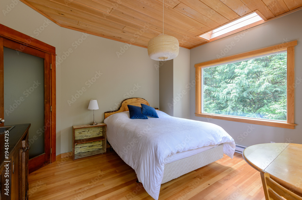 Bright bedroom with great forest view in a rustic cottage. Home interior.