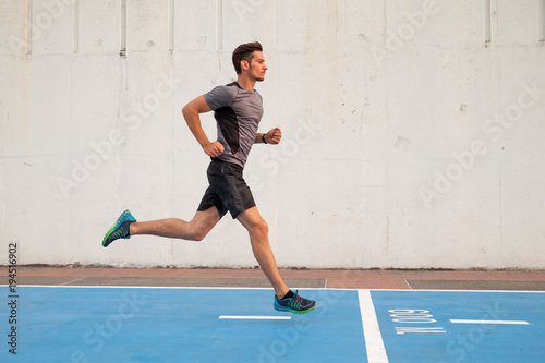 Side view of confident young man looking forward while running photo