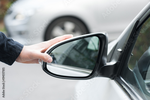 Young human hand is preparing or correct car mirror for the trip or travel from car window.