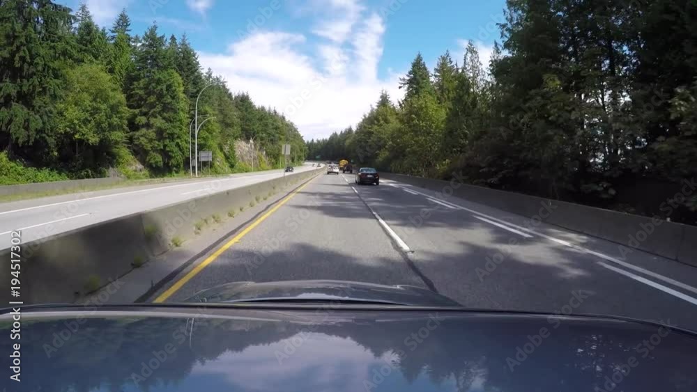 Driving along Highway 99 through a mountain forest under clear blue sky Driving along Highway 99 through a mountain forest under clear blue sky
