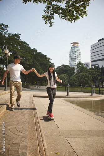 Young people use skatboard for relaxing time together outdoor at the city in the park
