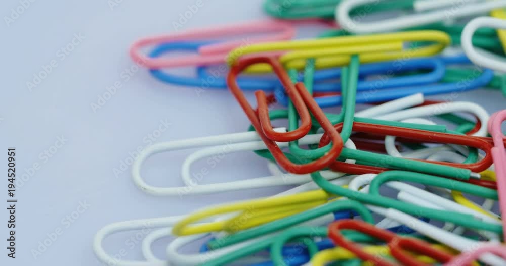 Top view on the rolling paper clips in colours lying on the white background. Macro shooting Top view on the rolling paper clips in colours lying on the white background. Macro shooting