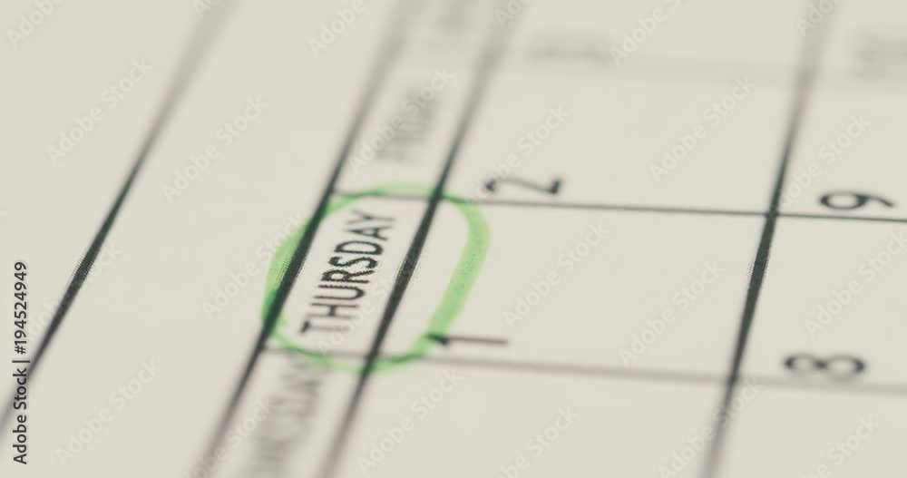 Close up of the female hand encircle Thursday on the paper with a calendar. Macro shooting