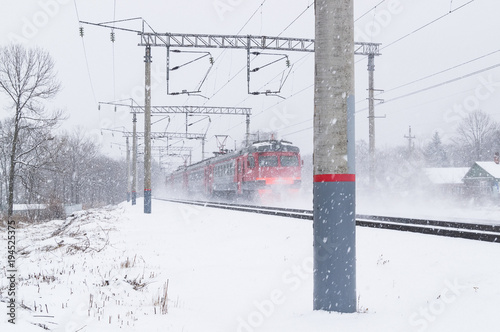 The passenger electric train moves during a blizzard in the winter